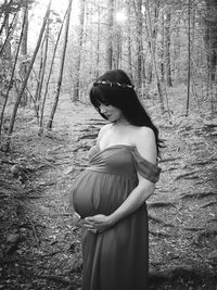 Woman standing by tree trunk in forest