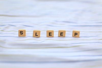 Close-up of sleep text made with toy blocks on bed