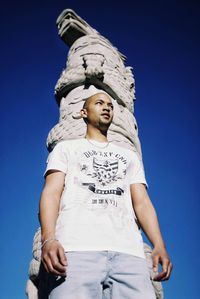 Low angle view of young man against clear blue sky