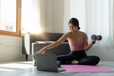 Side view of young woman exercising in office
