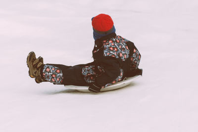 Side view of boy tobogganing on snow