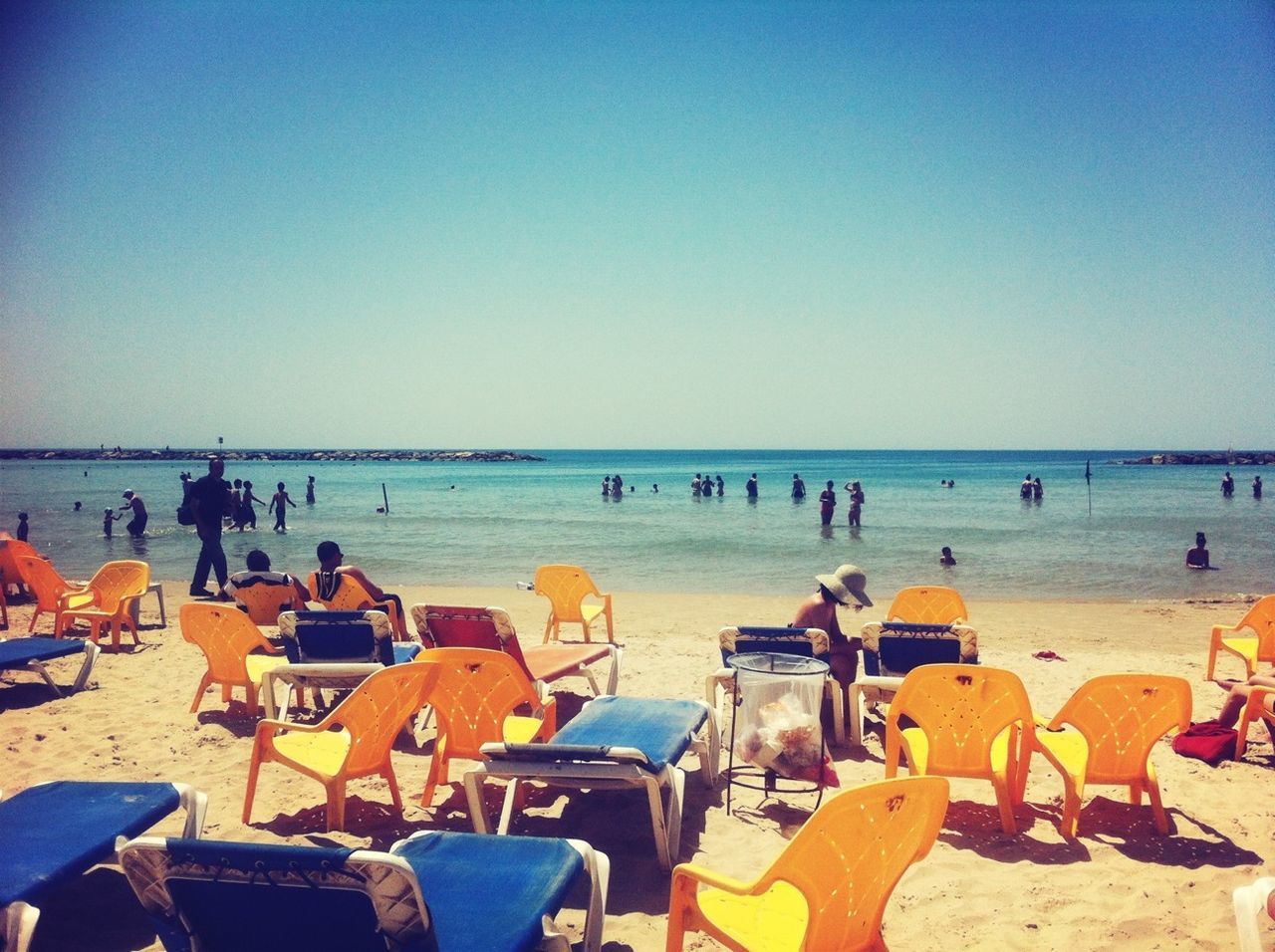 sea, beach, horizon over water, water, sand, large group of people, clear sky, shore, vacations, chair, relaxation, copy space, beach umbrella, leisure activity, parasol, person, lounge chair, men, lifestyles