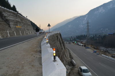 Vehicles on road by mountain against sky