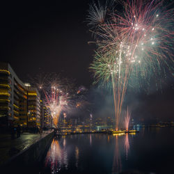 Firework display in city by river at night