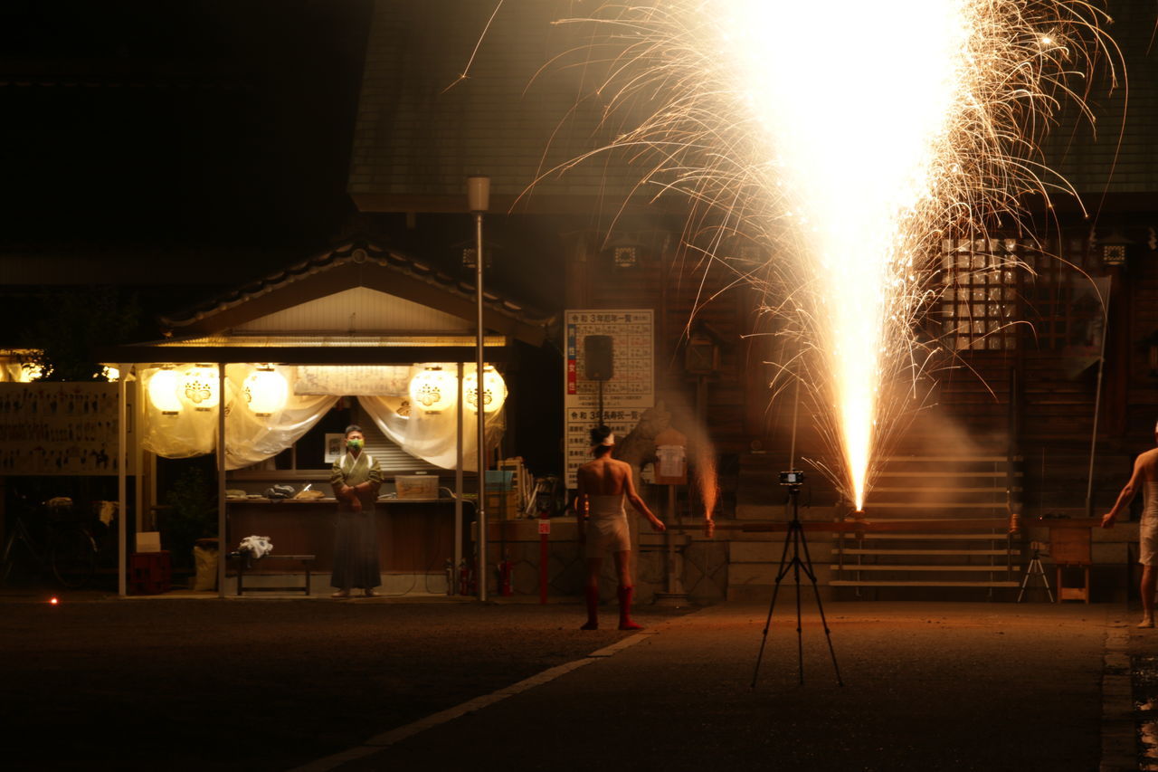 BLURRED MOTION OF MAN WITH UMBRELLA STANDING AT NIGHT