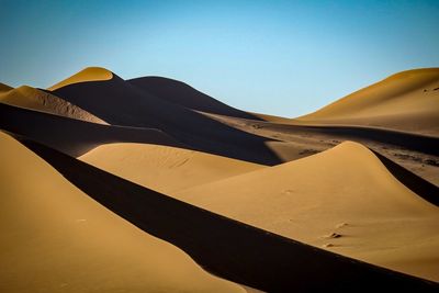 Low angle view of sand dunes against clear sky