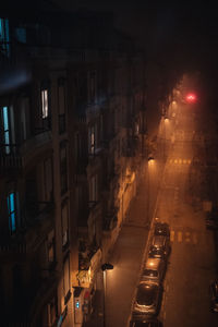 Illuminated street amidst buildings in city at night