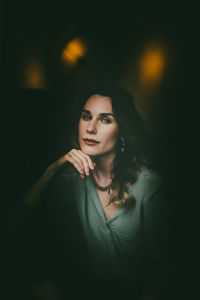 Portrait of young woman against black background