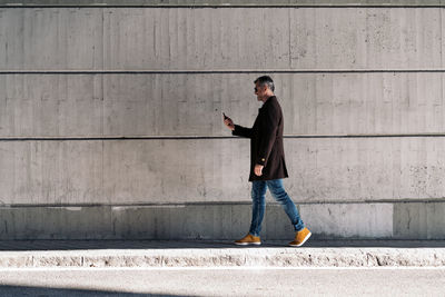 Full length side view of a man standing on footpath