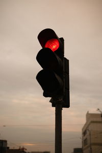 Low angle view of road signal against sky during sunset