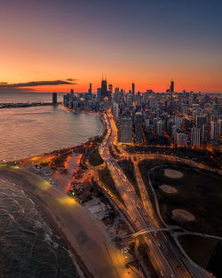 High angle view of illuminated road by buildings against sky during sunset