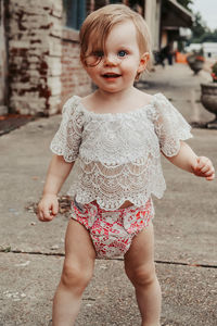 Portrait of cute girl standing on footpath