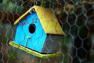 Close-up of birdhouse hanging on fence