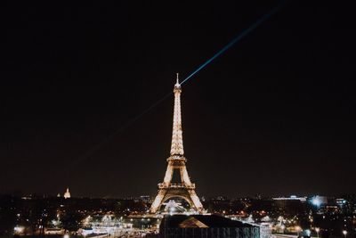 Communications tower in city against sky at night