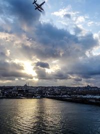 City at waterfront against cloudy sky