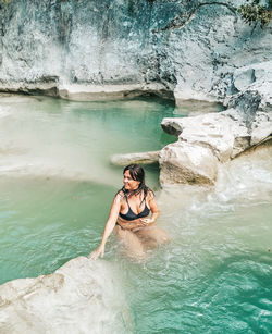 Young woman in bikini on rock at sea