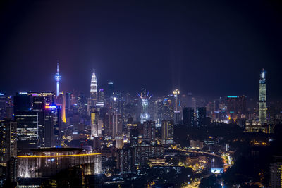 Illuminated buildings in city against sky at night