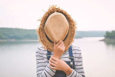 Close-up of boy wearing hat against lake