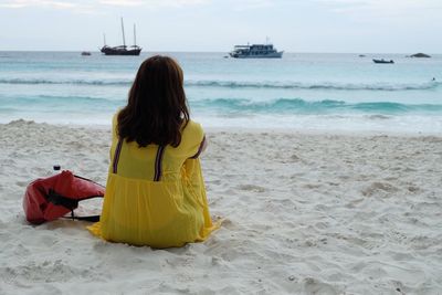 Rear view of woman sitting at beach