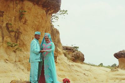 Wedding couple standing against rock formation