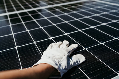 Hand of mature technician man touching solar panels on house roof for self consumption energy