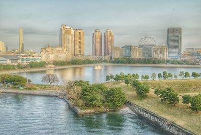 River by city buildings against sky