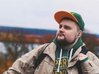 Young man listening music against sky