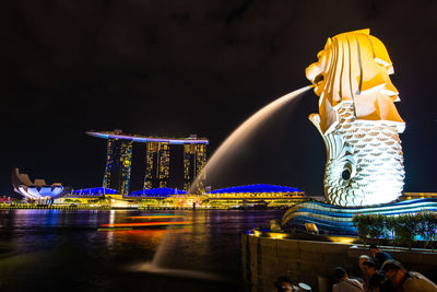 Statue in illuminated city against clear sky at night