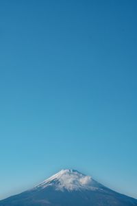 Snowcapped landscape against clear blue sky