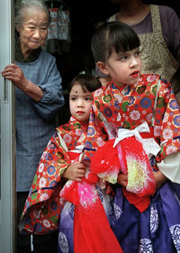 Girls in traditional clothing standing with mother and grandmother