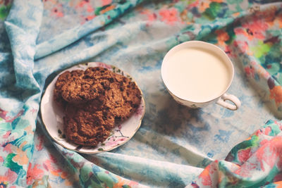 High angle view of cookies in plate with milk on table