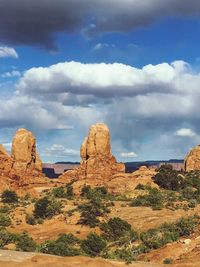 Rock formations on landscape against cloudy sky