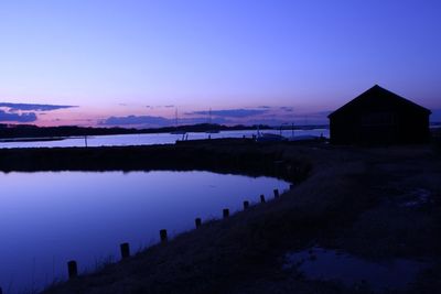 Scenic view of lake by buildings against sky at sunset