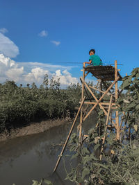 Man sitting on land against blue sky