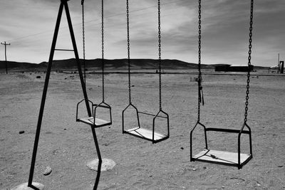 Empty swing in playground against sky