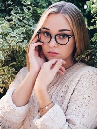 Portrait of young woman wearing eyeglasses amidst plants