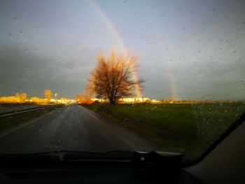 Road amidst trees against sky seen through car windshield