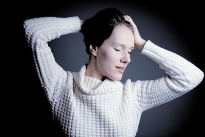 Close-up portrait of young woman against black background