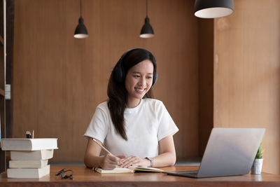 Young woman using laptop at desk in office