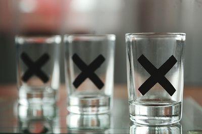 Close-up of cross shape on empty shot glasses at table