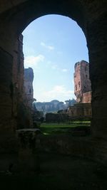 Ruins of temple against sky seen through arch