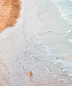 Aerial view of mature man with surfboard at beach