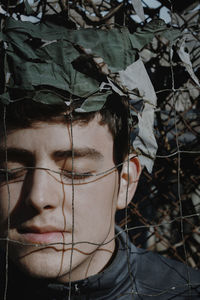Close-up of young man with eyes closed behind nets