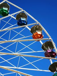 Low angle view of ferris wheel against clear blue sky