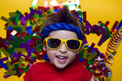 Child a boy in a red t shirt and sunglasses is lying on yellow paper resting at home