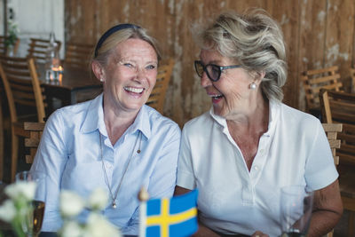 Smiling senior female friends talking and socializing at table in restaurant