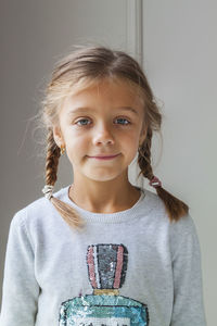 Portrait of smiling girl standing against wall