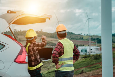 Rear view of men working against sky