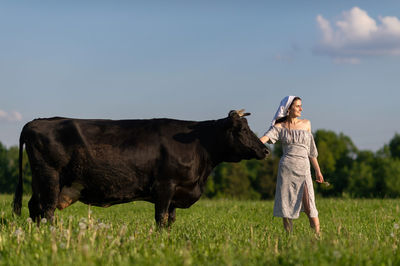 Side view of woman with horse on field against sky