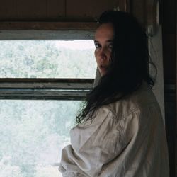 Portrait of beautiful woman by window at home